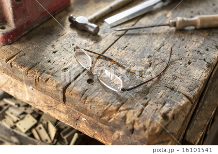 Antique furniture restorer's workbench. A worn marked block of wood with smoothed edges, a hammer and chisel, and spectacles. Antique furniture restorer's workbench. A worn marked block of wood with smoothed edges, a hammer and chisel, and spectacles. 16101541