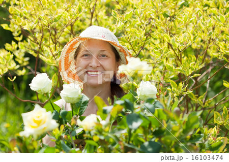 Happy mature woman in roses plant 16103474