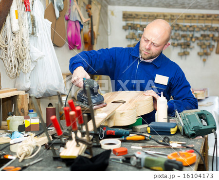 craftsman working with unfinished guitar 16104173