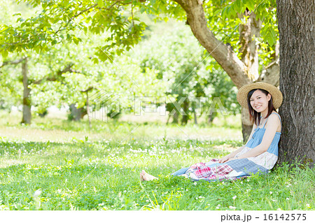 初夏の公園で木陰に座り休む女性の写真素材