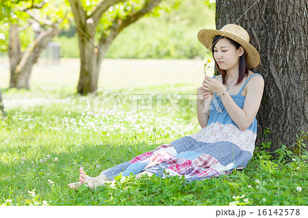 初夏の公園で木陰に座り休む女性の写真素材