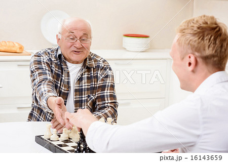 Grandson and grandfather playing chess in kitchen  16143659