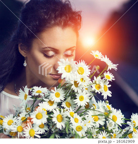 Toned image of young beautiful dreamy women with bouquet of flowers. 16162909