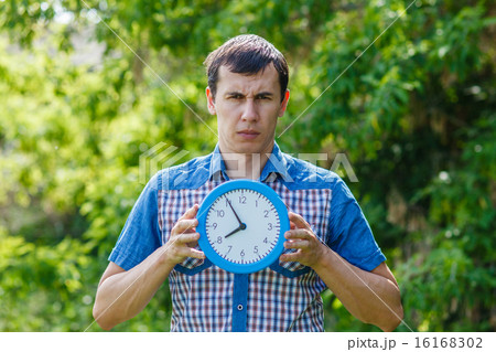 man holding a clock with both hands on a green  background  Summ 16168302