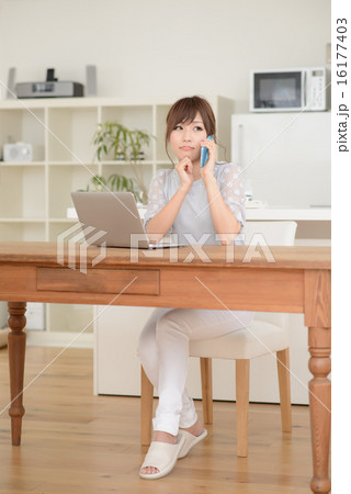 スマートフォンで電話する若い女性・ノートパソコン 16177403