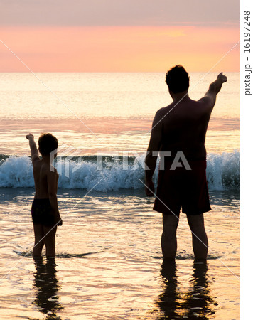 Father and son in front of evening sky seaside 16197248