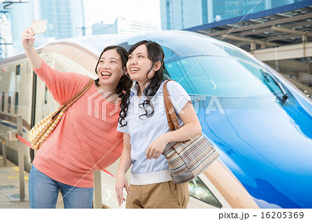 北陸新幹線の前で記念写真を撮っている若い女性2人 16205369