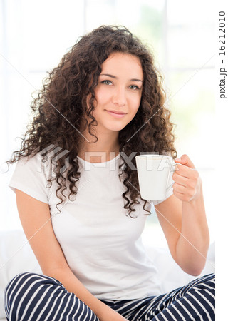 Young woman having morning coffee or tea 16212010