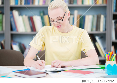 Happy student with glasses writing in library Happy student with glasses writing in library 16212442