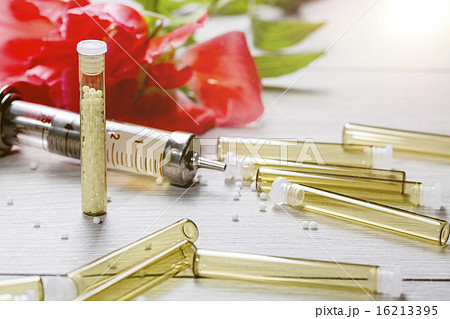 small glass tubes with homeopathic medicine, syringe and flower 16213395