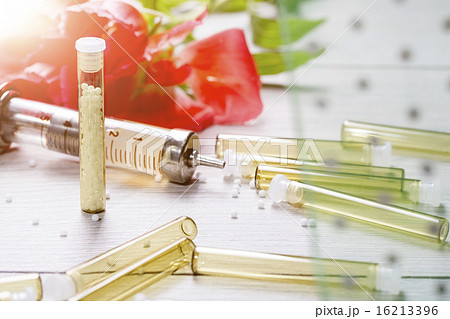 small glass tubes with homeopathic medicine, syringe and flower 16213396