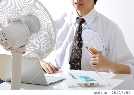 夏の暑いオフィスで扇風機をかけながら仕事をするビジネスマン男性 夏の暑いオフィスで扇風機をかけながら仕事をするビジネスマン男性 16217266
