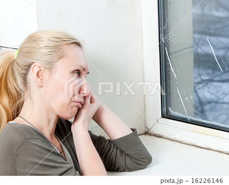 sad young woman near a window with the burst, brok 16226146