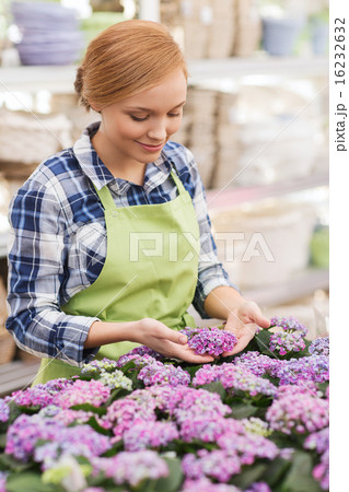 happy woman taking care of flowers in greenhouse 16232632