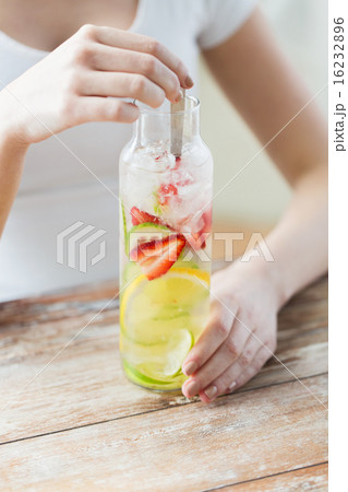 close up of woman with fruit water in glass bottle close up of woman with fruit water in glass bottle 16232896