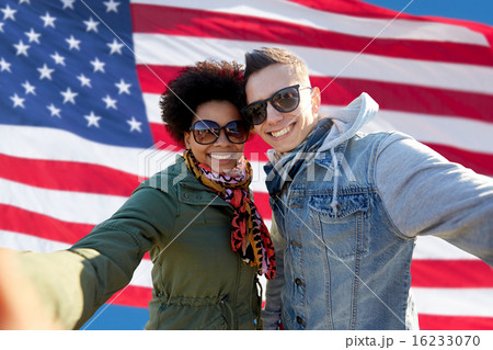 happy couple taking selfie over american flag 16233070