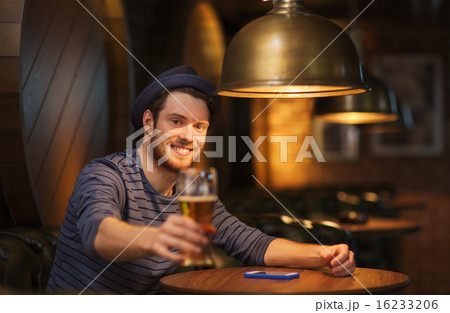 happy man drinking beer at bar or pub 16233206