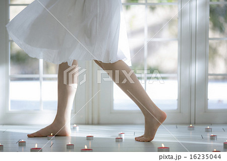 キャンドルが置かれた床を歩く女性の足の写真素材
