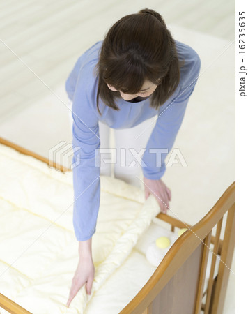 ベビーベッドを整える母親 16235635