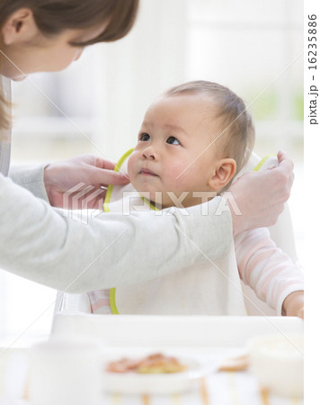 母親にスタイをつけてもらう赤ちゃん 16235886