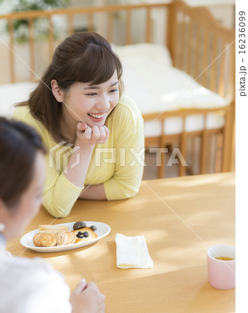 カップを持って会話しながら笑う女性 16236099