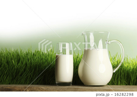 Glass of milk and jar on meadow 16282298