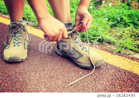 young woman hiker tying shoelaces in the nature 16282495