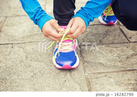 young asian woman tying shoelace on stone trail young asian woman tying shoelace on stone trail 16282790