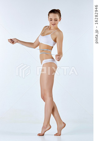 Woman holding meter measuring perfect shape of her beautiful body  16282946