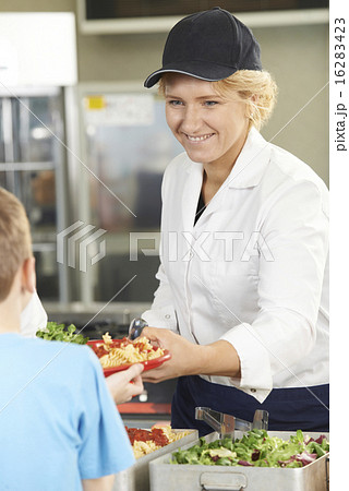 Pupil In School Cafeteria Being Served Lunch By Dinner Lady Pupil In School Cafeteria Being Served Lunch By Dinner Lady 16283423