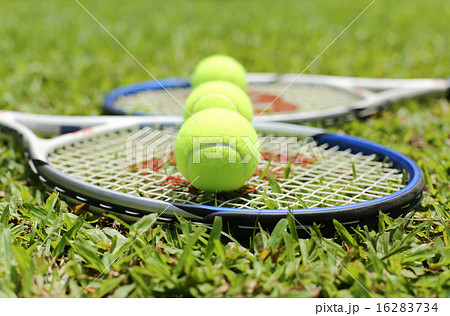 Tennis racket with tennis balls on the grass 16283734