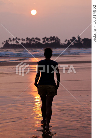 Woman walking on beach at sunset 16314902