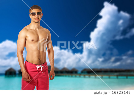 Man on beach with water bungalows Man on beach with water bungalows 16328145