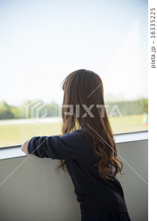 窓の外を見る若い女性の写真素材