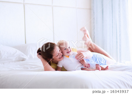 Mother and baby relaxing in white bedroom Mother and baby relaxing in white bedroom 16343937
