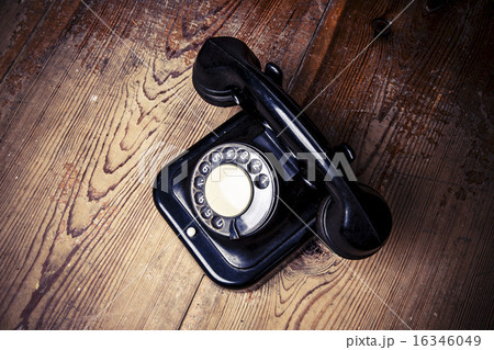 Old black phone with dust and scratches on  floor 16346049