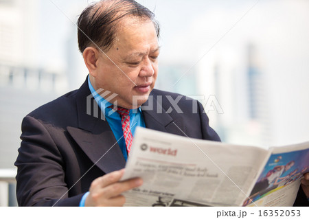 Asian senior businessman in suit reading newspaper 16352053