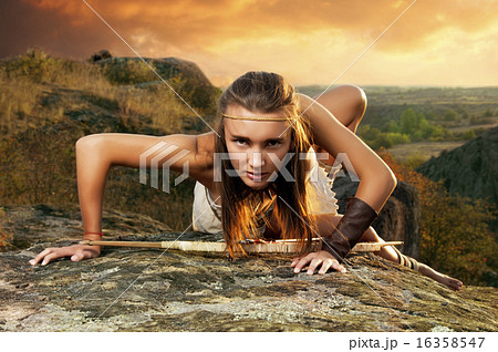 Primitive woman on a rock at the sunset. Amazon woman Primitive woman on a rock at the sunset. Amazon woman 16358547
