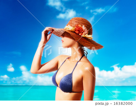 夏休み 麦わら帽子とビキニでビーチにたたずむ女性の写真素材