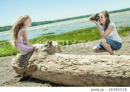 Cheerful mother taking picture of her cute little daughter  16383528
