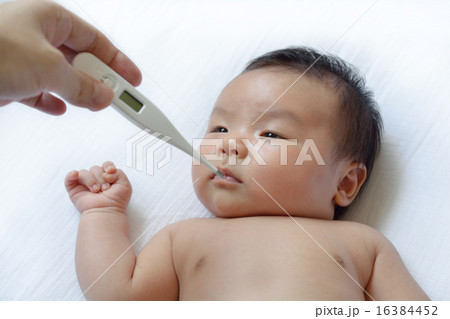 赤ちゃんの熱を測るお母さんの手の写真素材