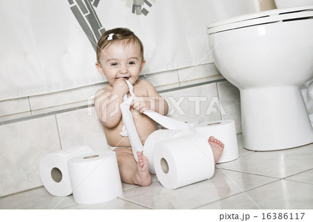 Toddler ripping up toilet paper in bathroom 16386117