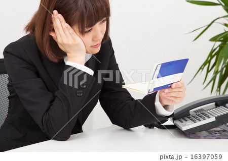 通帳を見て悩む女性 16397059
