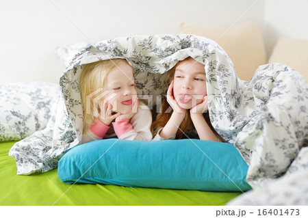 Two little sisters playing in bed 16401473
