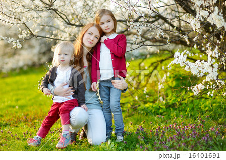 Young mother and her children in blooming garden Young mother and her children in blooming garden 16401691