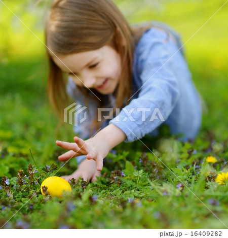 Adorable little girl hunting for an egg on Easter 16409282