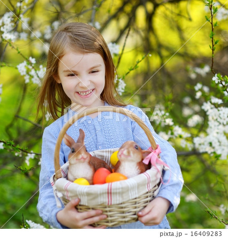Adorable girl holding a basket of Easter eggs Adorable girl holding a basket of Easter eggs 16409283