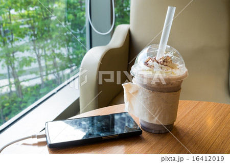 cell phone with a plastic cup of chocolate frappe cell phone with a plastic cup of chocolate frappe 16412019