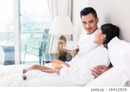Asian couple lounging in bed at morning Asian couple lounging in bed at morning 16412920
