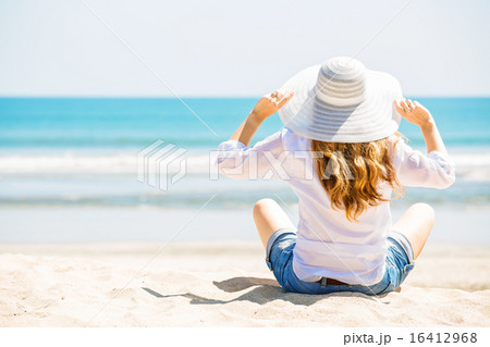 Beautifil young woman sitting on the beach at sunny day enjoing summer vacation 16412968